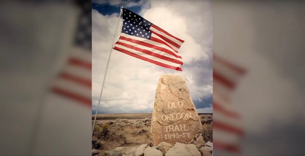 American flag next to a stone with the inscription Old Oregon Trail