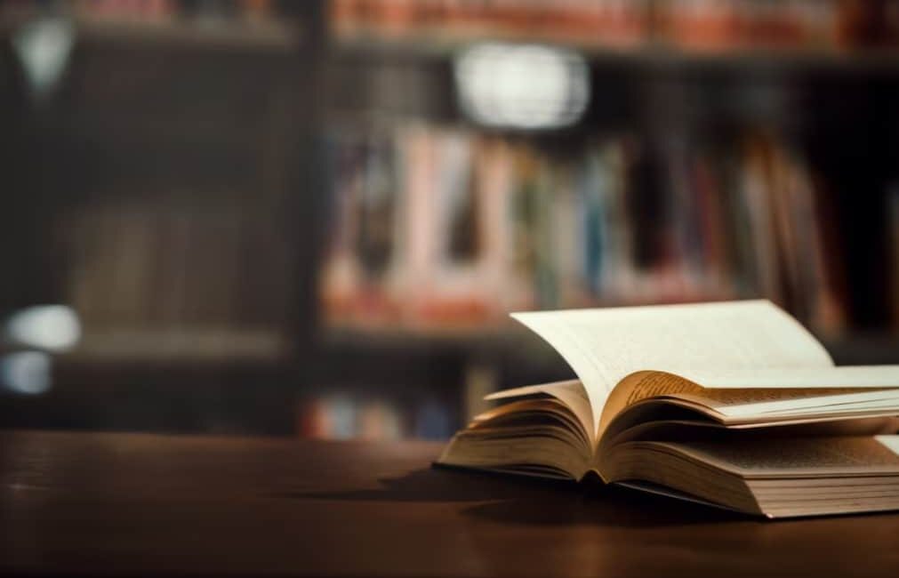 An open book on a table with a blurred library background