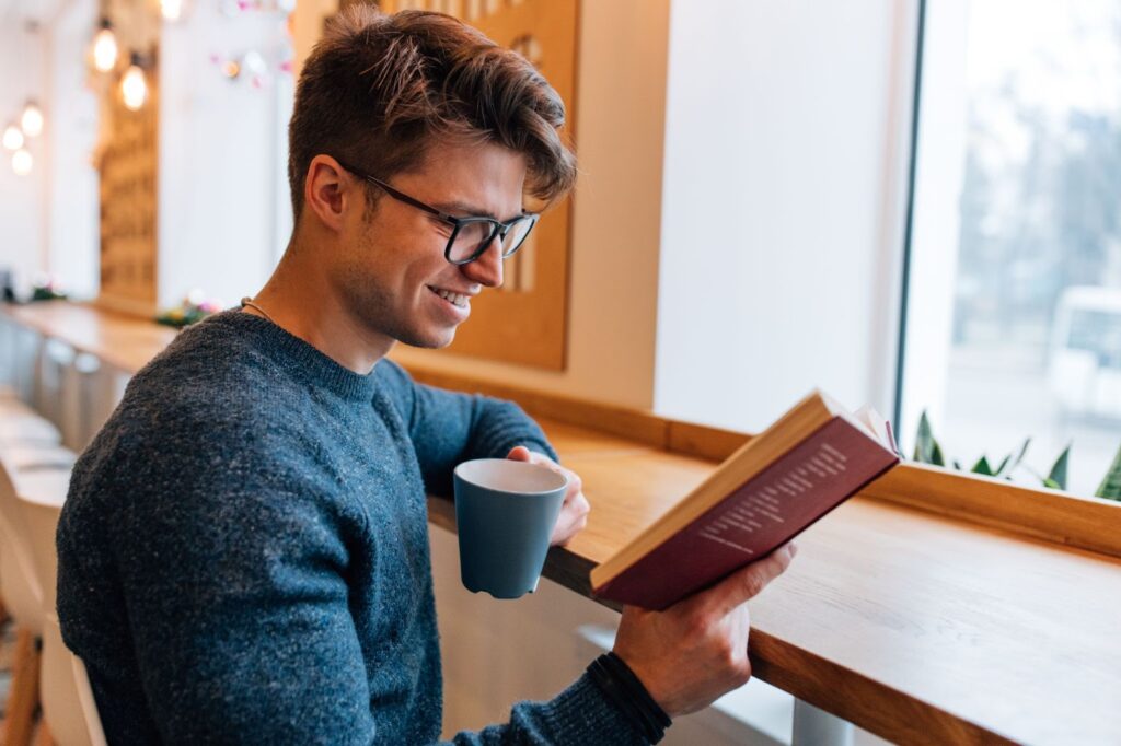 Man reading interesting book and drinking tea in the cafe