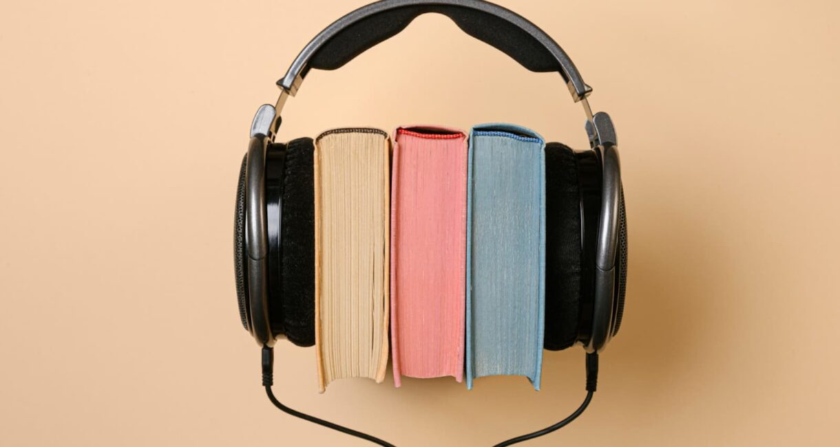 Three books with headphones on a beige background