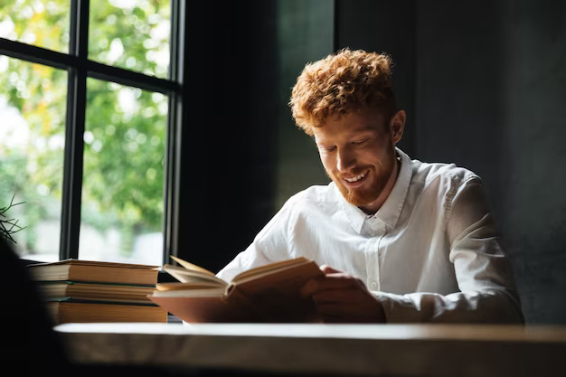 Guy reading a book near the window