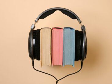 Three books with headphones on a beige background